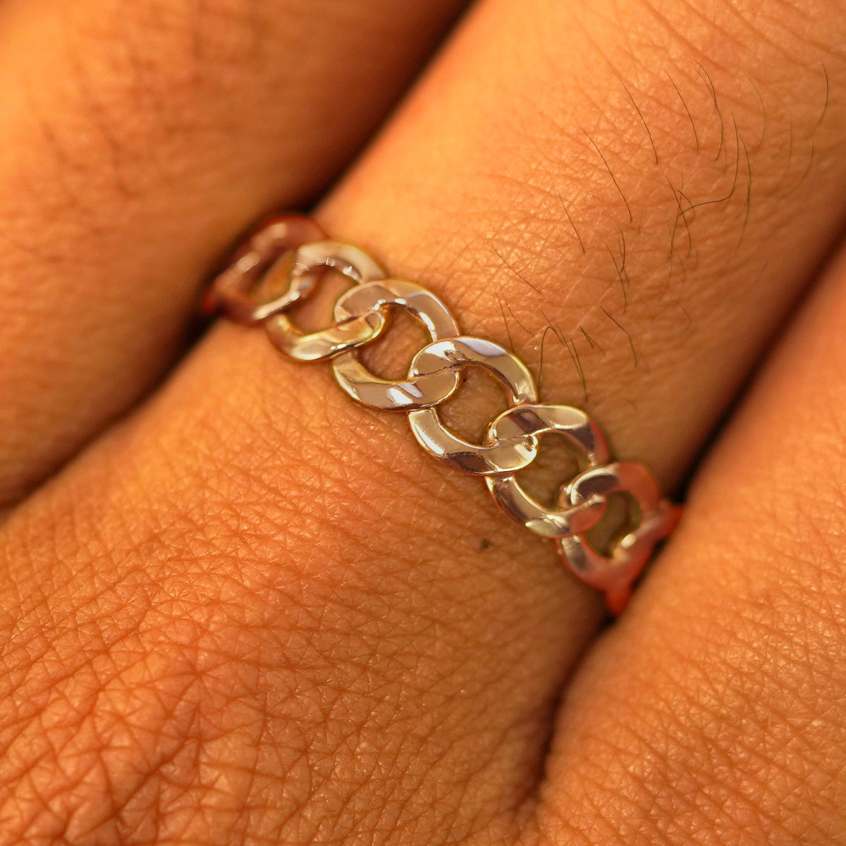 Close up view of a model's hand wearing a solid rose gold Curb Ring