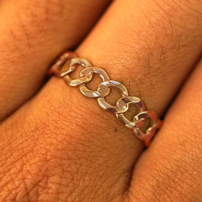 Close up view of a model's hand wearing a solid rose gold Curb Ring