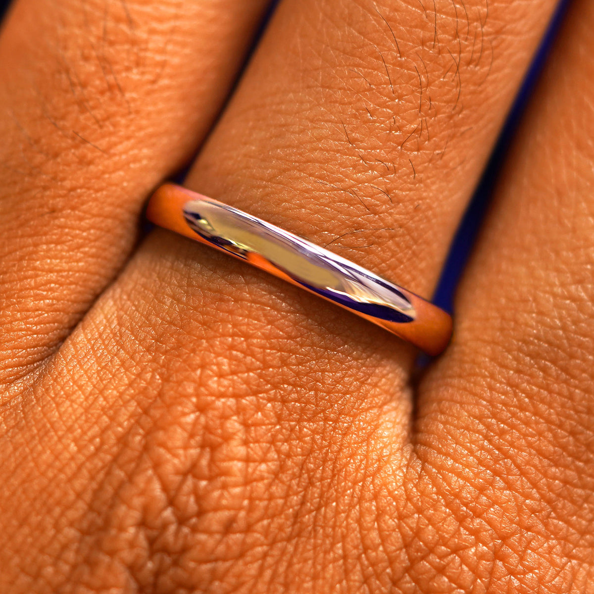 Close up view of a model's fingers wearing a 14k rose gold Curvy Mirror Band