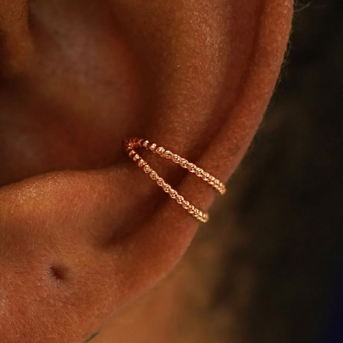 Close up view of a model's ear wearing a 14k rose gold Bead Ear Cuff