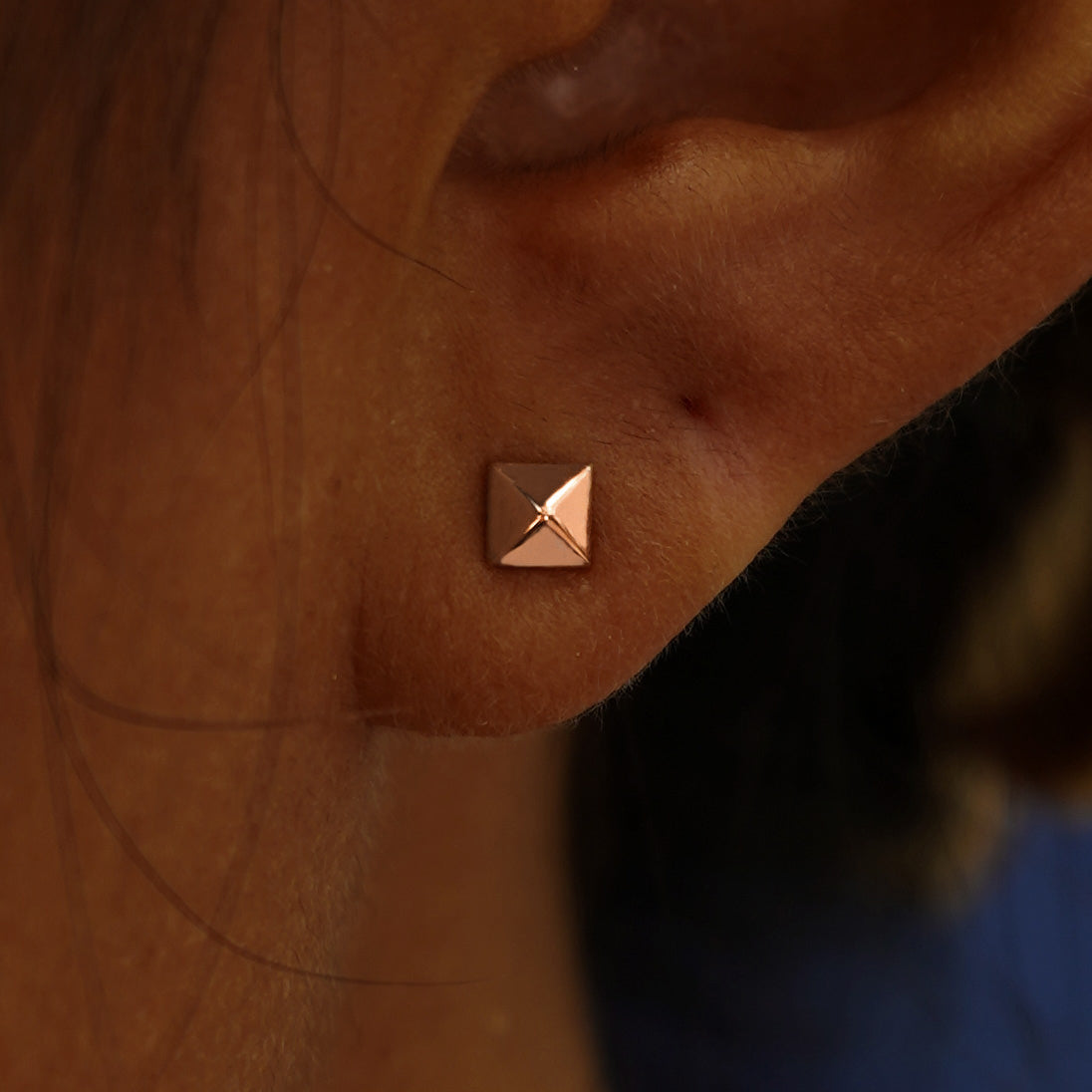 Close up view of a model's ear wearing a rose gold Pyramid Earring