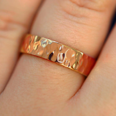 Close up view of a model's fingers wearing a 14k rose gold Industrial Hammered Band
