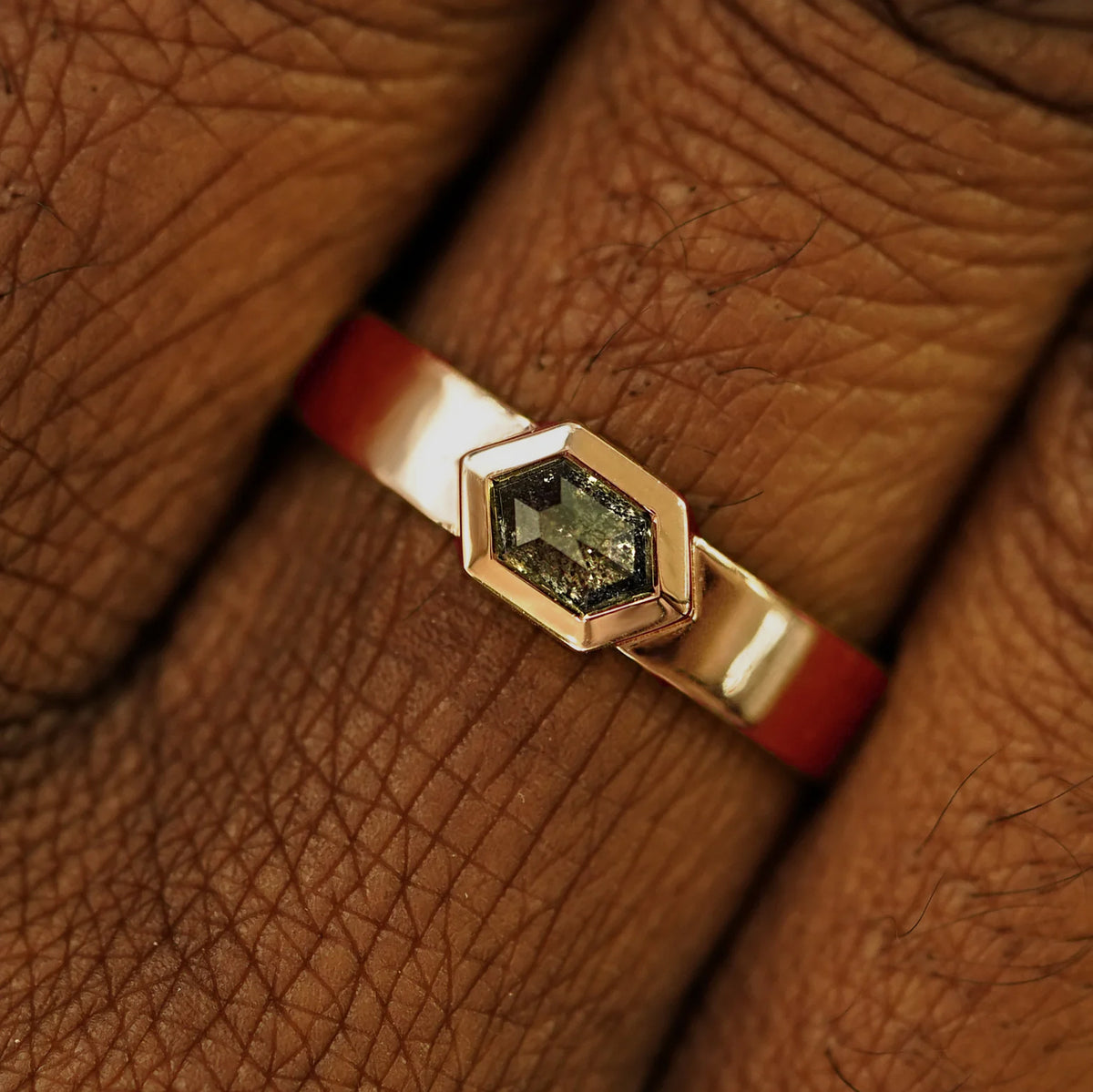 Close up view of a model's hand wearing a solid rose gold Hexagon Diamond Band