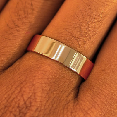 Close up view of a model's fingers wearing a 14k rose gold Industrial Mirror Band