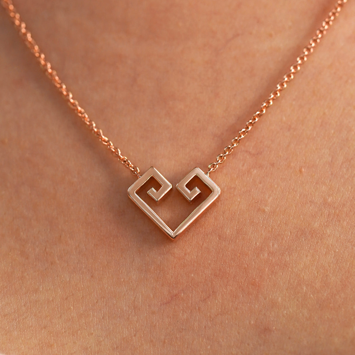 A close up view of a model's neck wearing a rose gold Large Chere Heart Necklace