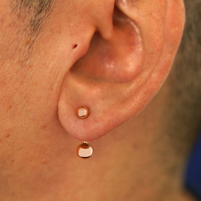 Close up view of a model's ear wearing a 14k rose gold Large Curved Barbell through a lobe piercing