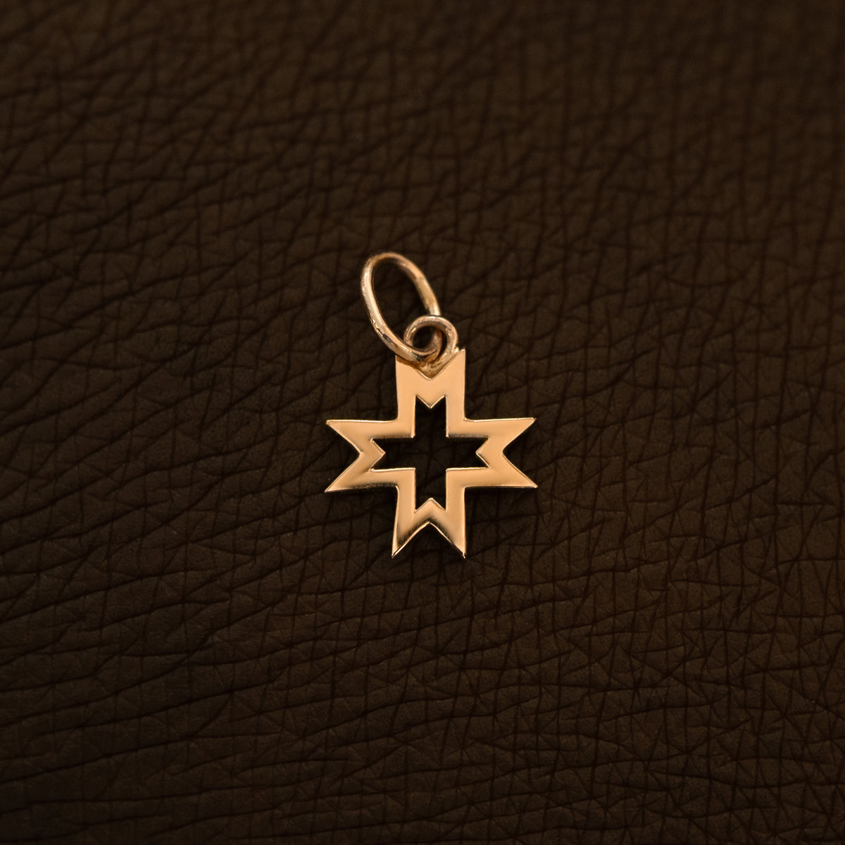 A 14 karat rose solid gold Large Open 8 Pointed Star Charm on the back of a model's hand