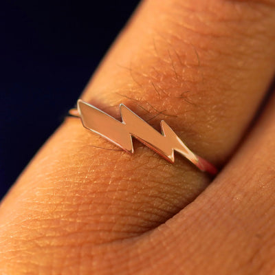 Close up view of a model's hand wearing a rose gold Lightning Bolt Ring