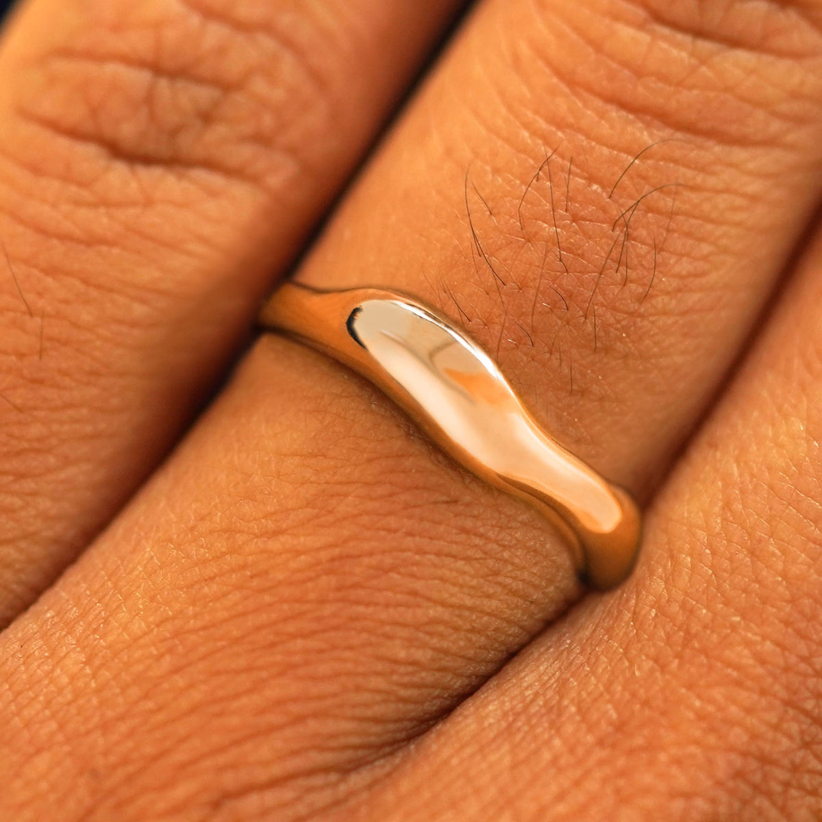 Close up view of a model's fingers wearing a 14k rose gold Liquid Band