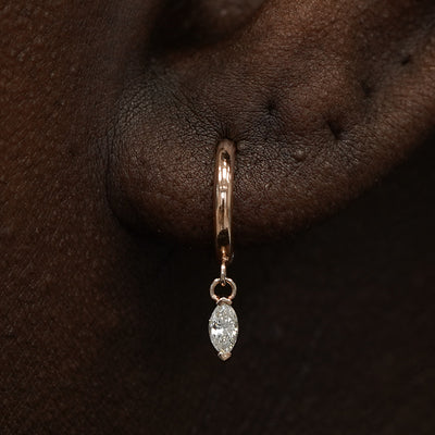 Close up view of a model's ear wearing a rose gold Marquise Lab Diamond Dangle Huggie Hoop