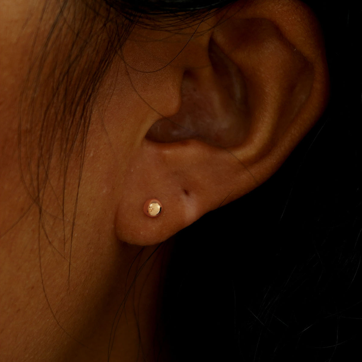 Close up view of a model's ear wearing a rose gold Medium Ball Earring