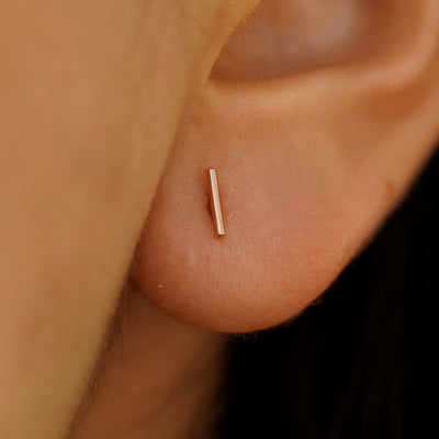 Close up of model's ear, they are wearing a rose gold Medium Line Earring.