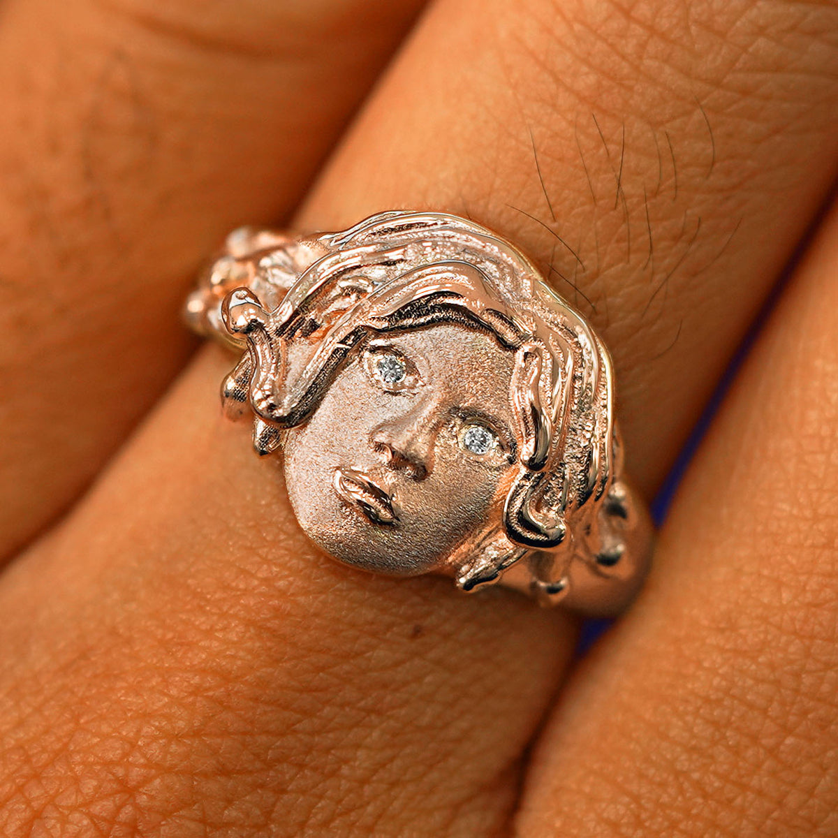 Close up view of a model's fingers wearing a 14k rose gold Medusa Ring