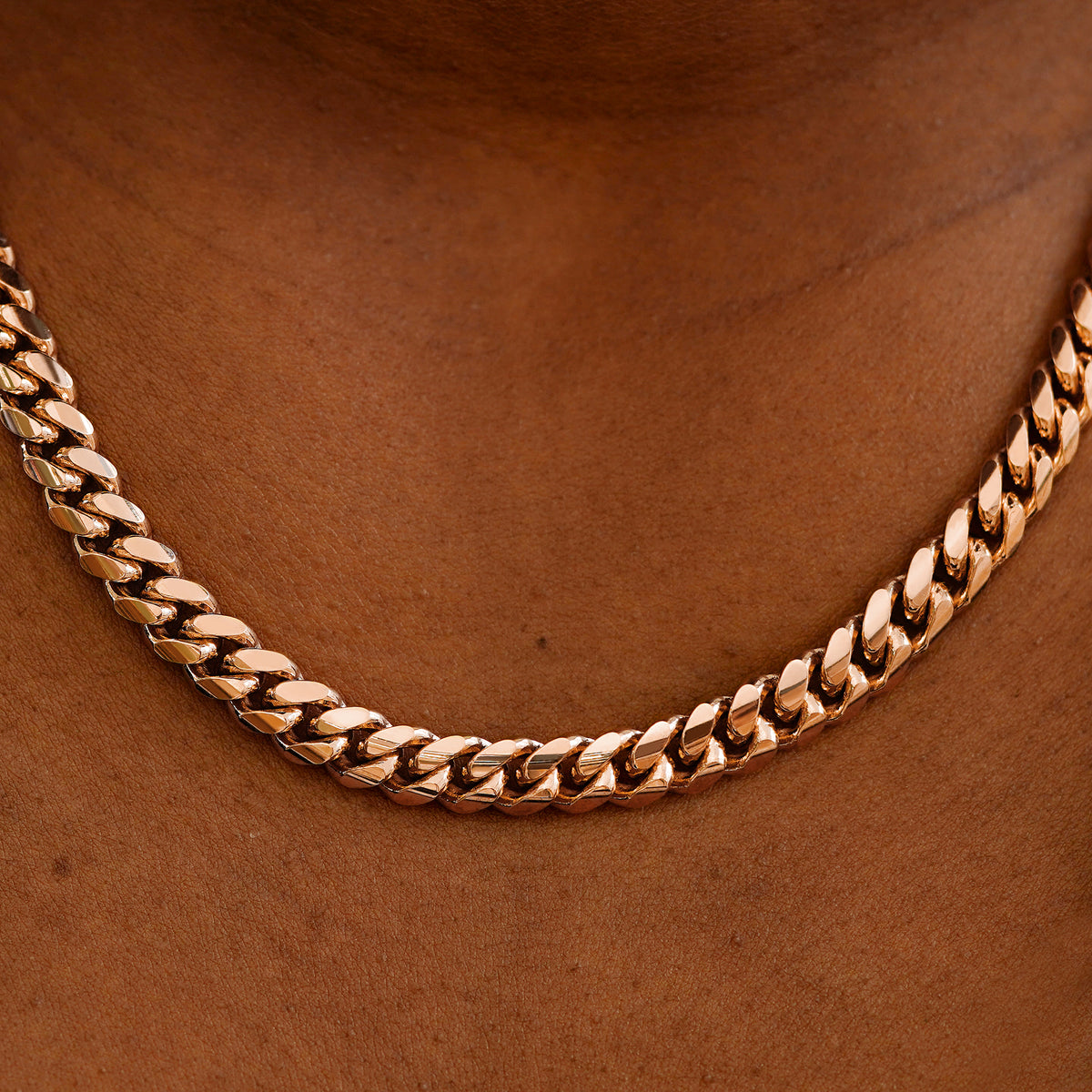 Close up view of a model's neck wearing a rose gold Miami Cuban Chain