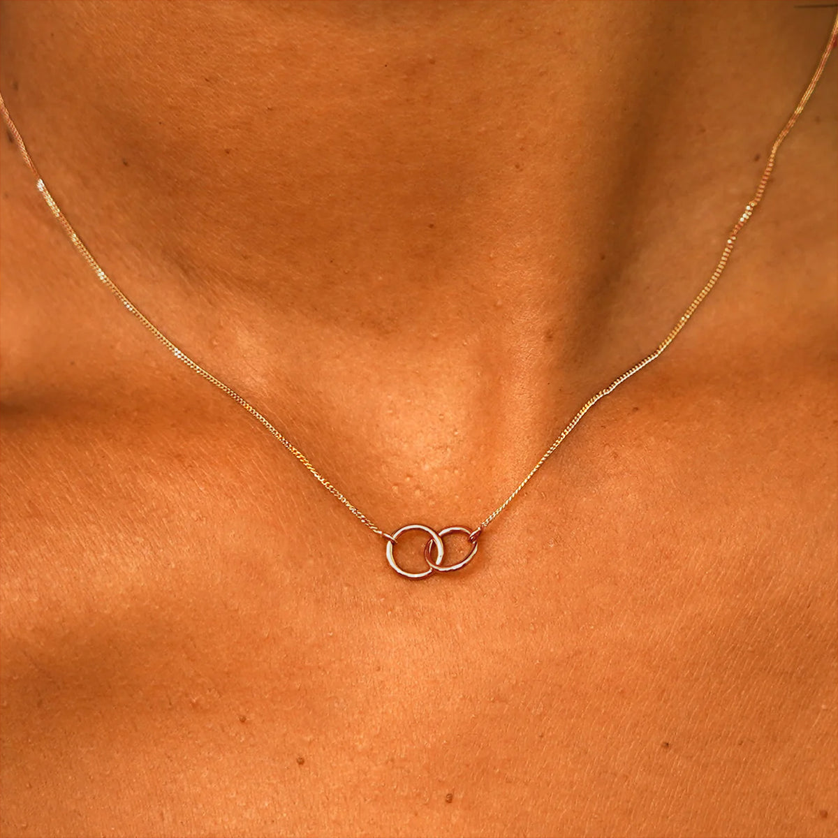 Close up view of a model's neck wearing a solid rose gold Mini Bound Together Necklace