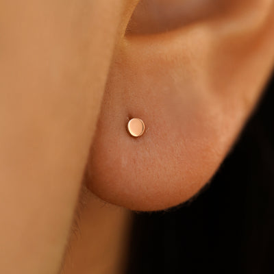 Close up of model's ear, they are wearing a rose gold Mini Circle Earring.