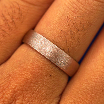 Close up view of a model's fingers wearing a 14k rose gold Mix Stardust Band