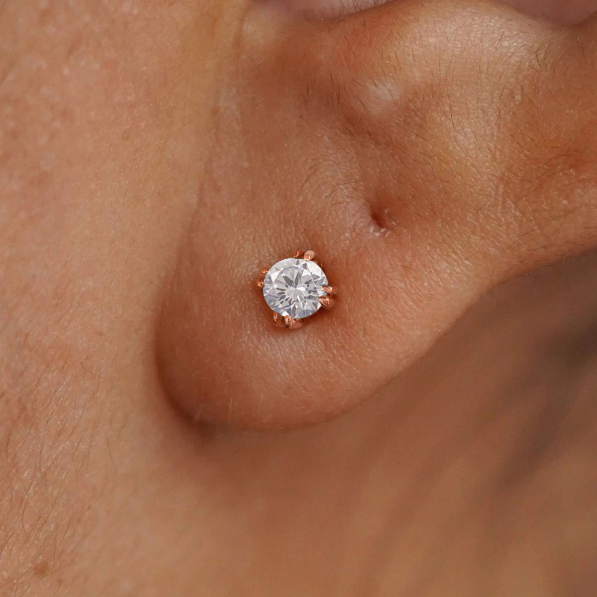 Close up view of a model's ear wearing a 14k yellow gold Moissanite Stud Earring