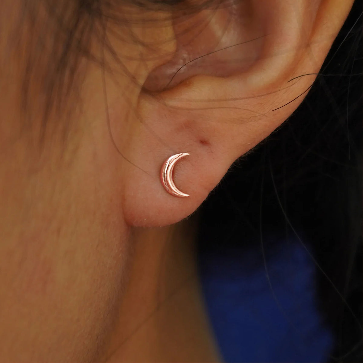 Close up view of a model's ear wearing a rose gold Moon Flat Back Earring