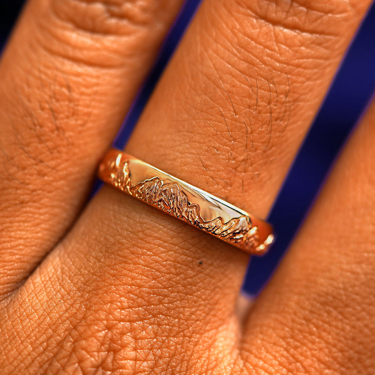 Close up view of a model's fingers wearing a 14k rose gold Mountains Band