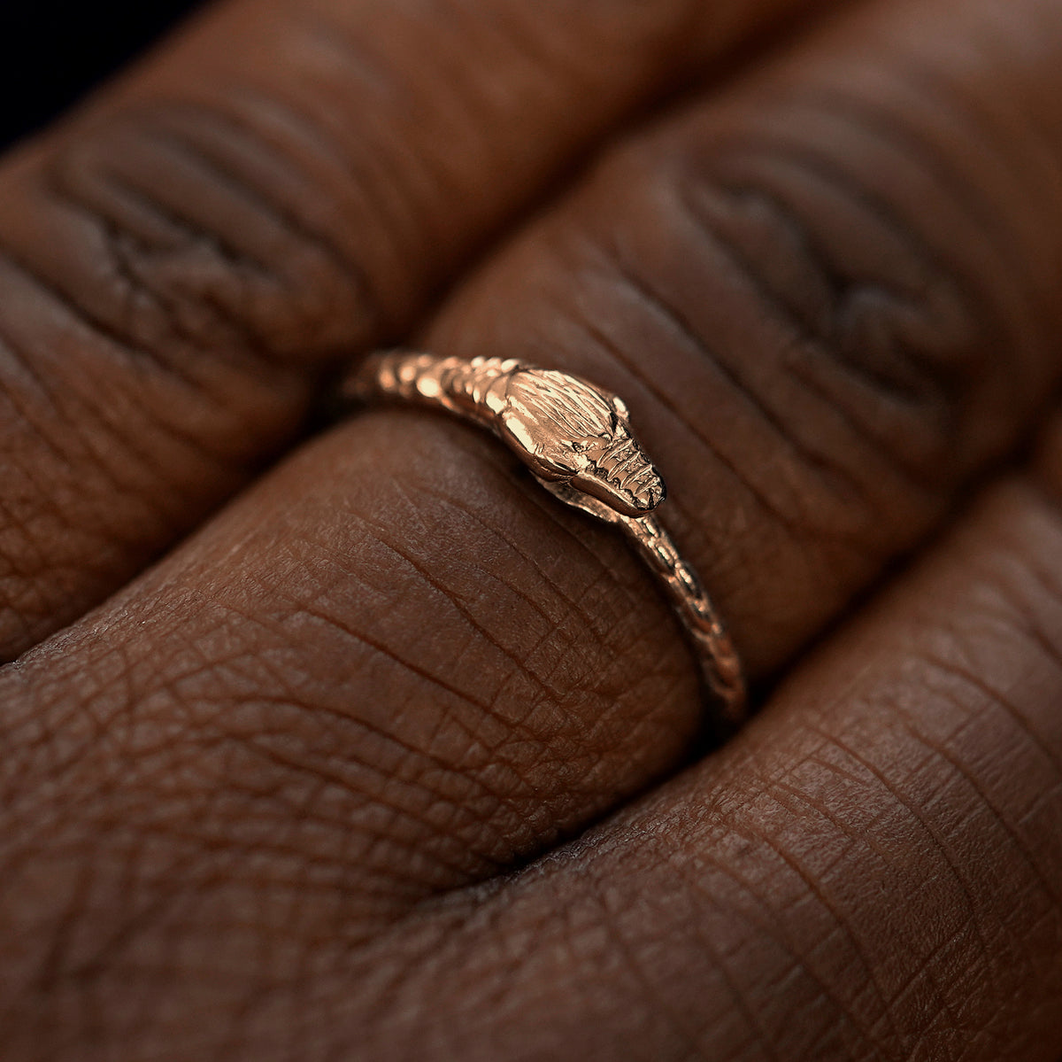 Close up view of a model's hand wearing a rose gold Ouroboros Snake Ring