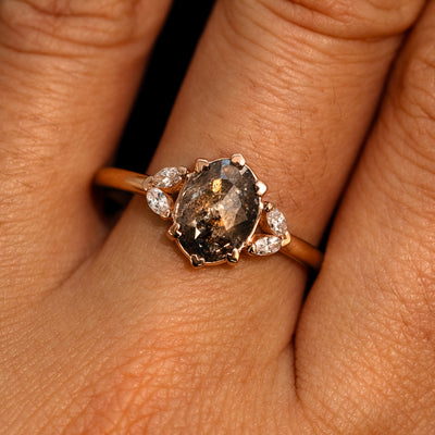 A model's hand wearing a 14k rose gold Oval Salt and Pepper Diamond Heart Prong Ring