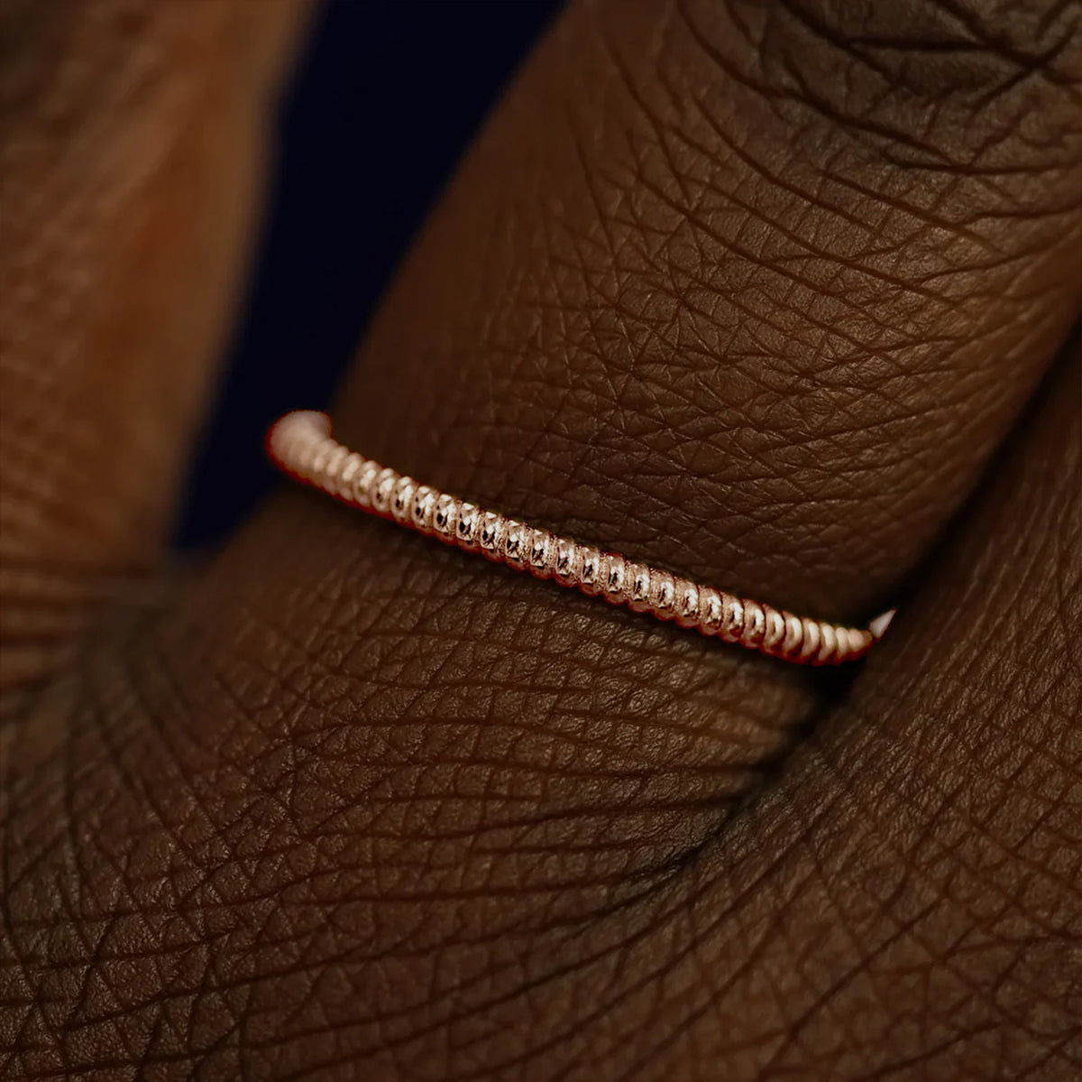 Close up view of a model's fingers wearing a 14k rose gold Rope Ring