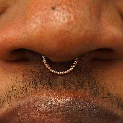 Close up view of a model's nose wearing a 14k rose gold Rope Septum