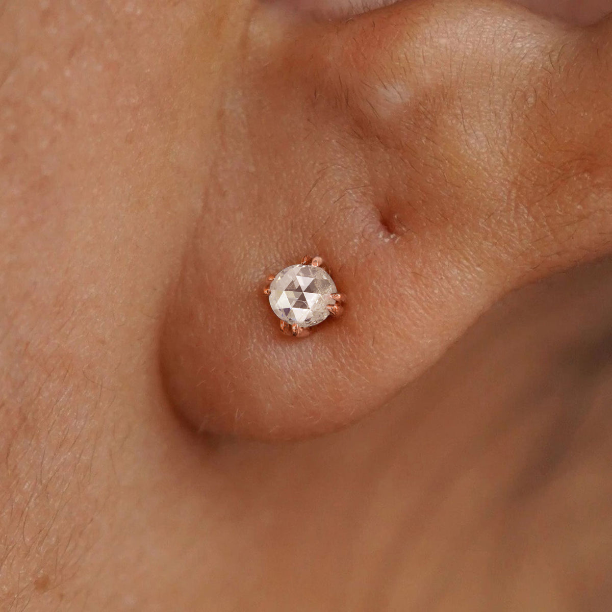 A model's ear wearing a 14k solid rose gold Rose Cut Diamond Earring
