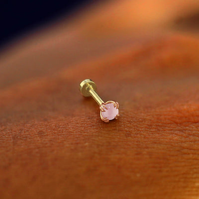 A solid 14k rose gold Rose Quartz Flatback Piercing resting on the back of a model's hand