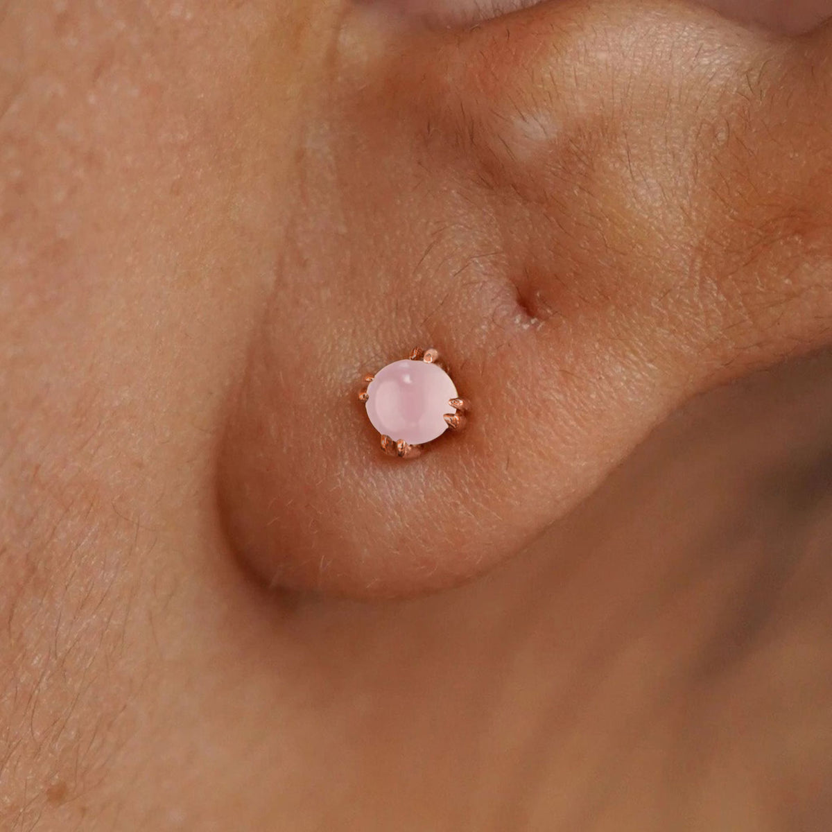 Close up view of a model's ear wearing a 14k rose gold Rose Quartz Earring
