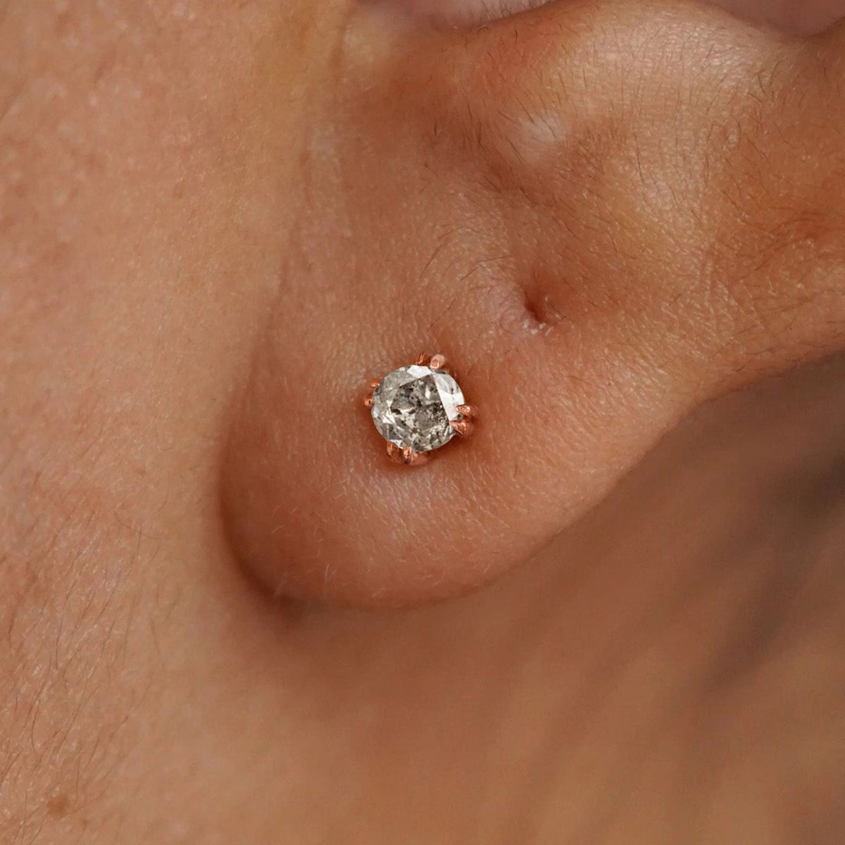 A model's ear wearing a 14k rose gold Salt and Pepper Diamond Earring