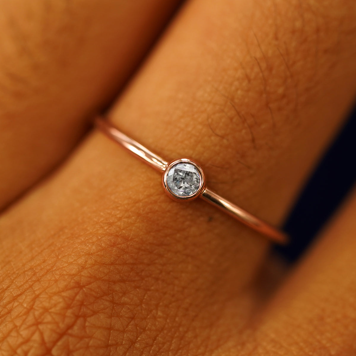 Close up view of a model's fingers wearing a 14k rose gold Salt and Pepper Diamond Ring