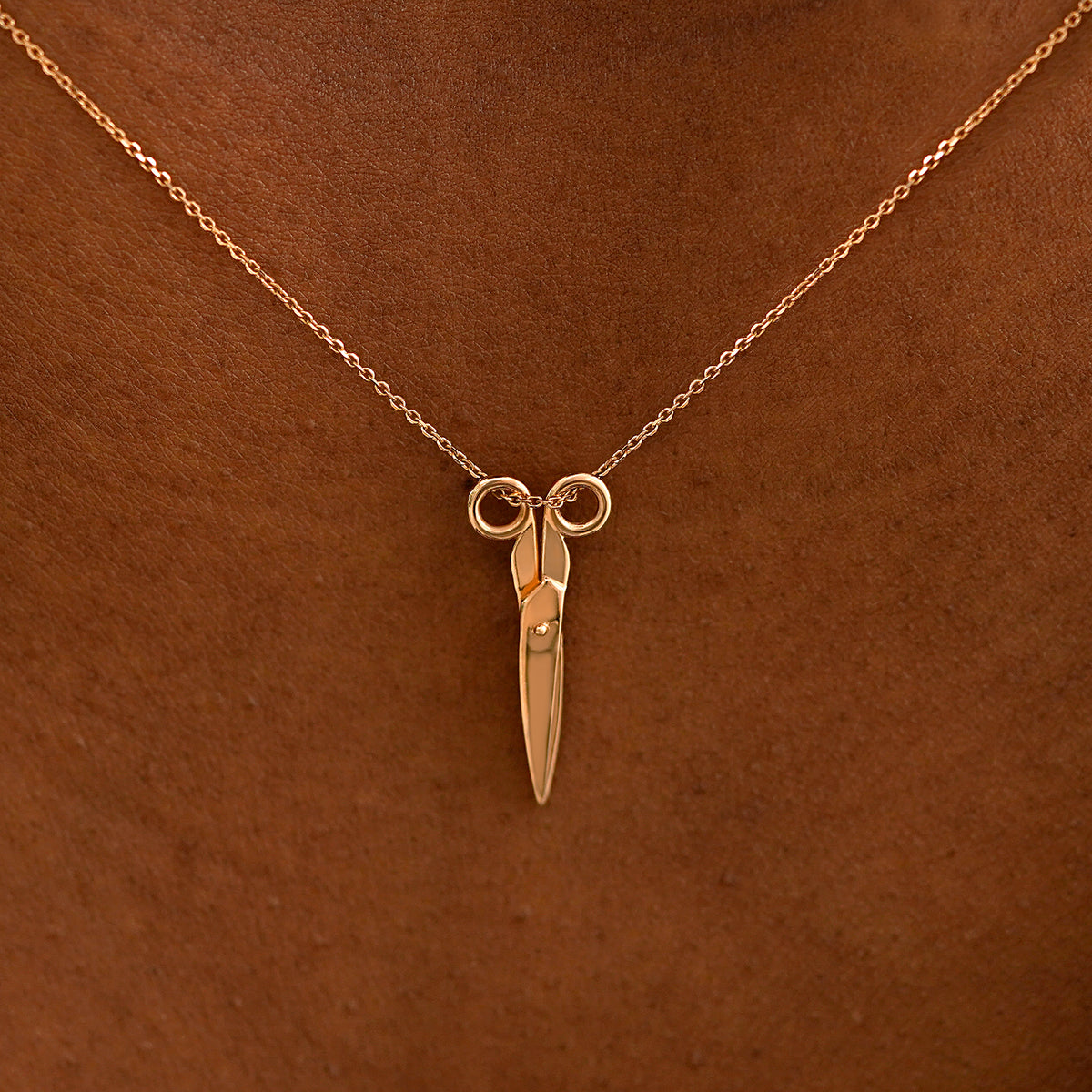 Close up view of a model's neck wearing a solid 14k rose gold Scissors Necklace