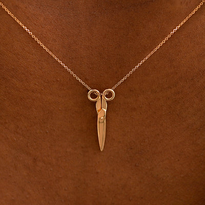 Close up view of a model's neck wearing a solid 14k rose gold Scissors Necklace