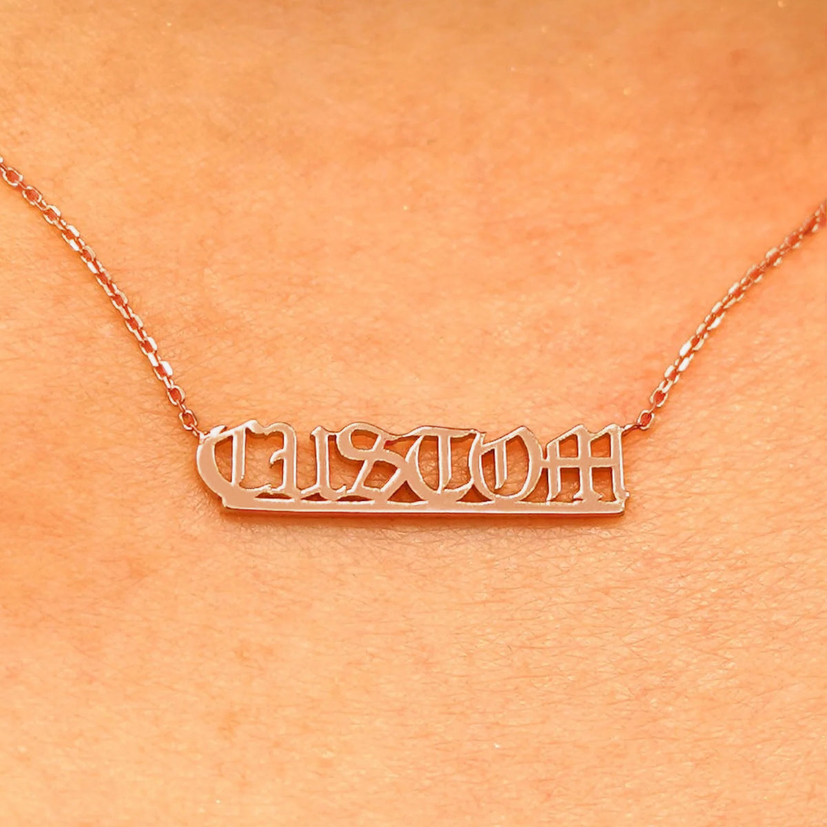 Close up view of a model's neck wearing a rose gold Small Custom Nameplate necklace that says Custom