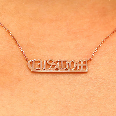 Close up view of a model's neck wearing a rose gold Small Custom Nameplate necklace that says Custom