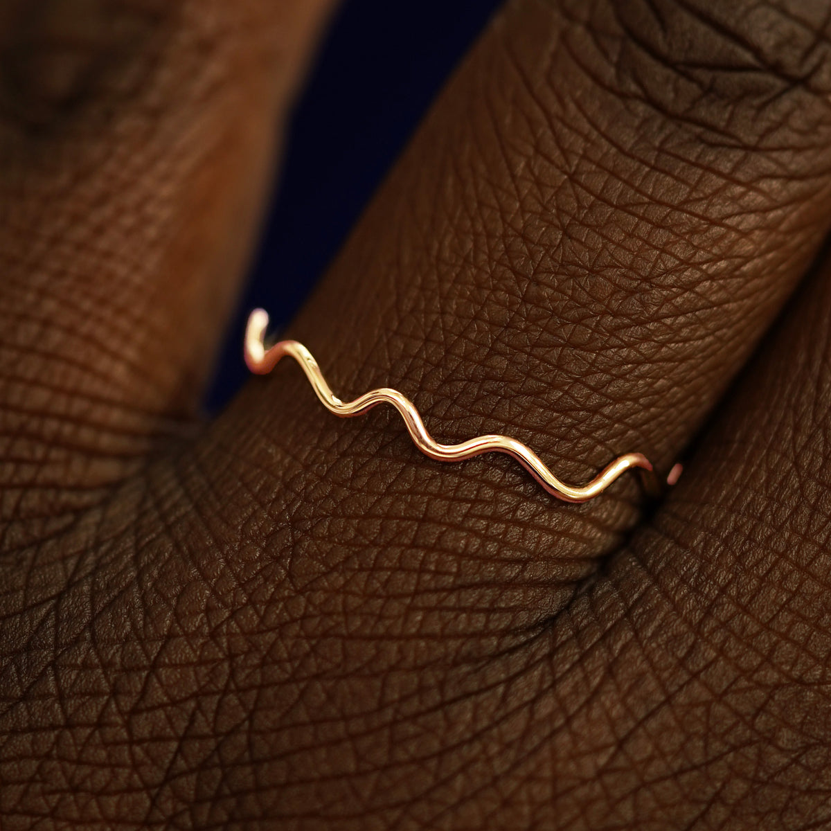 Close up view of a model's hand wearing a solid rose gold Wave Ring
