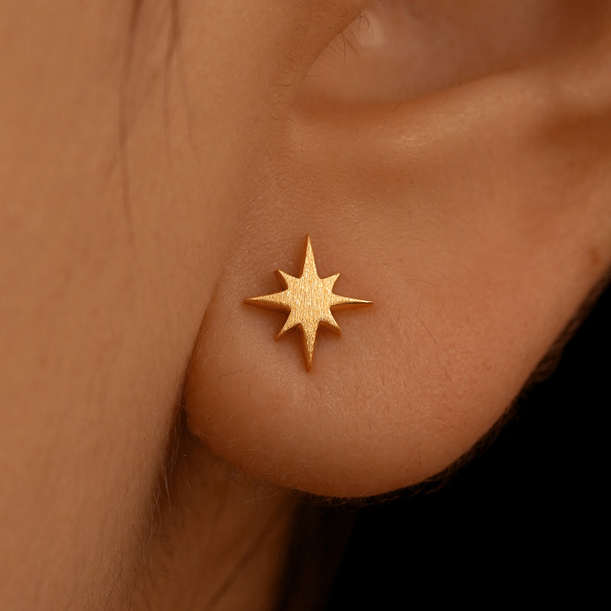 Close up view of a model's ear wearing a 14k rose gold Starburst Earring