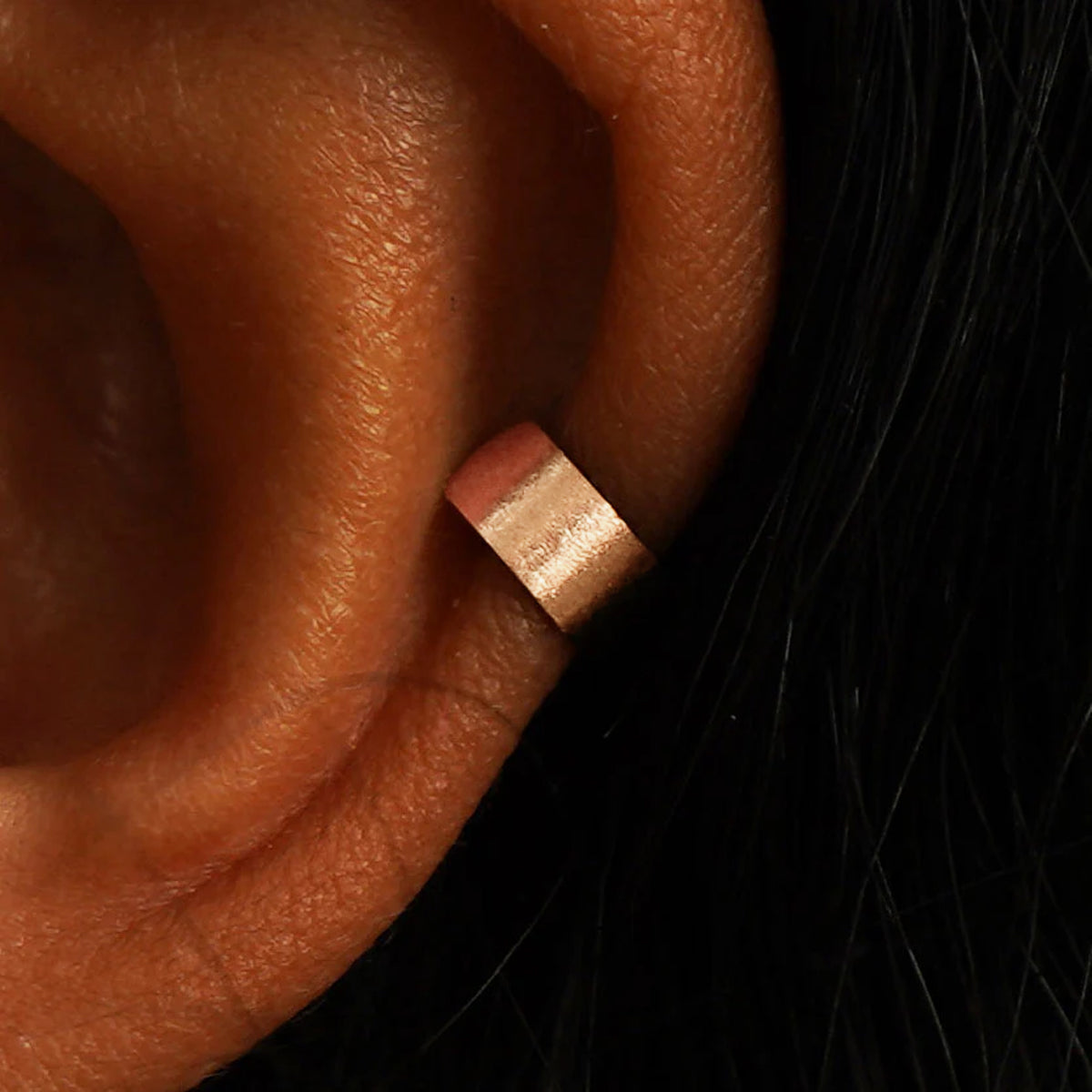 Close up view of a model's ear wearing a 14k rose gold Stardust Thick Cuff