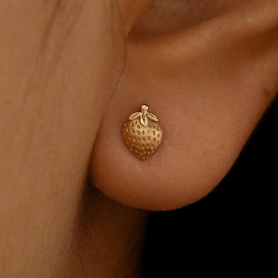 Close up view of a model's ear wearing a 14k rose gold Strawberry Earring