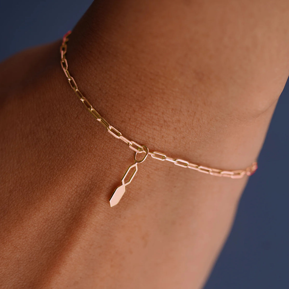 Close up view of a model's wrist wearing a rose gold Tanlah Charm on a Butch Bracelet