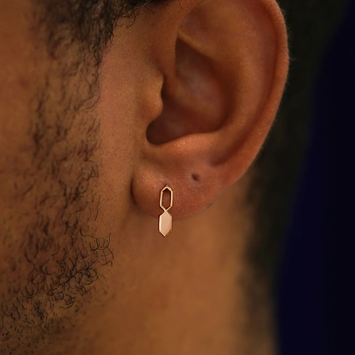 Close up view of a model's ear wearing a 14k rose gold Tanlah Earring vertically