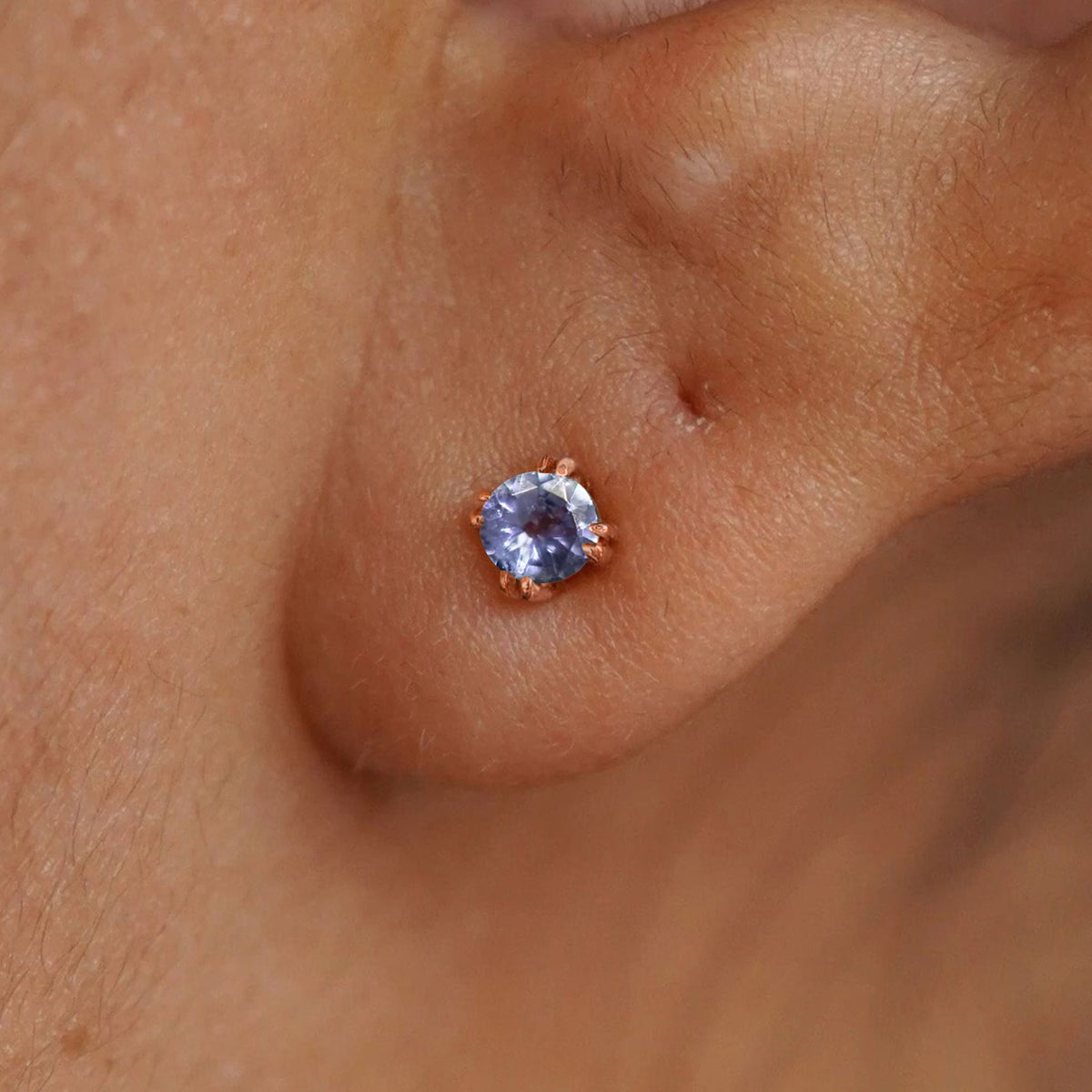 Close up view of a model's ear wearing a 14k rose gold Tanzanite Earring