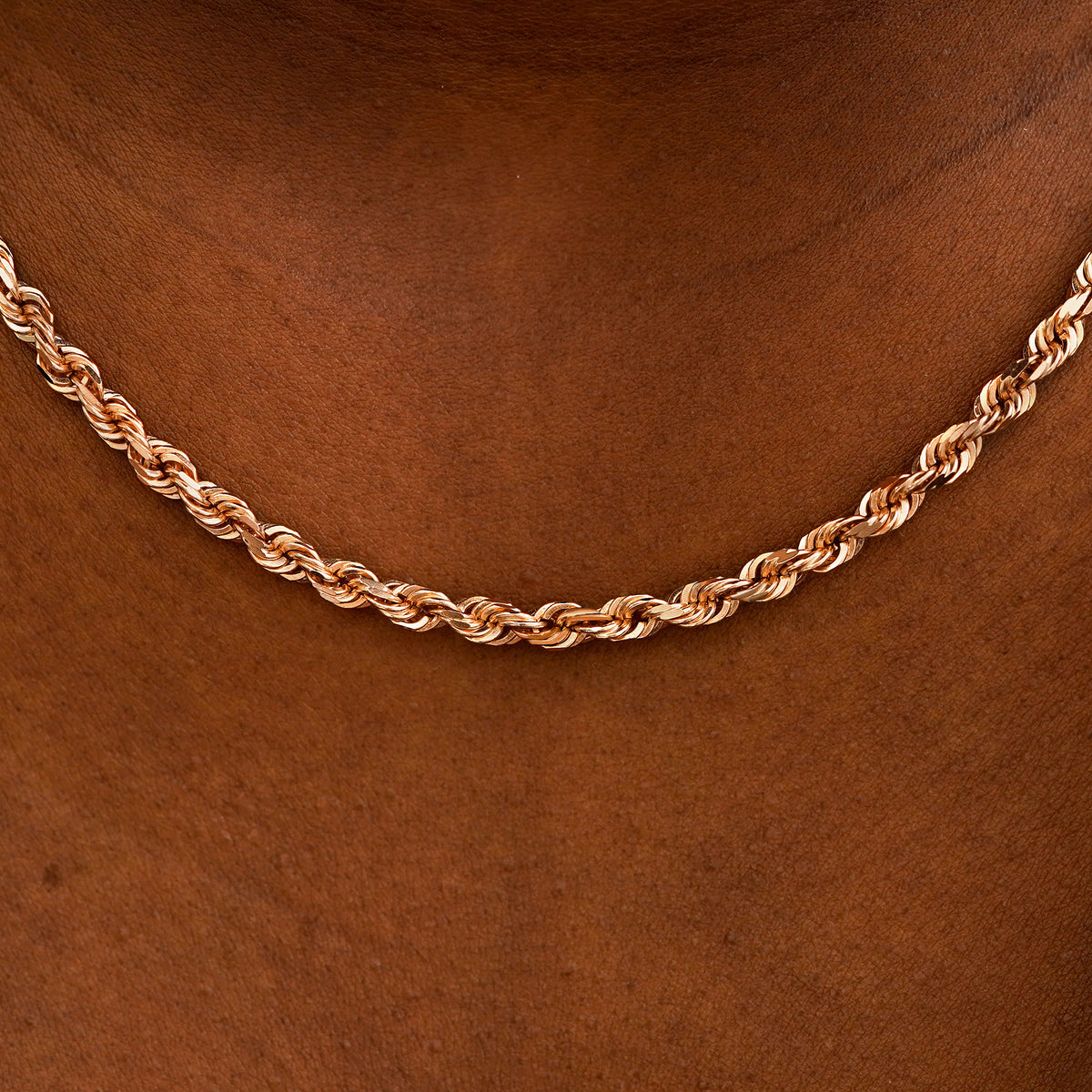 Close up view of a model's neck wearing rose gold thick rope chain