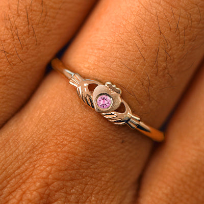 Close up view of a model's fingers wearing a 14k rose gold pink tourmaline Thin Gemstone Claddagh Ring