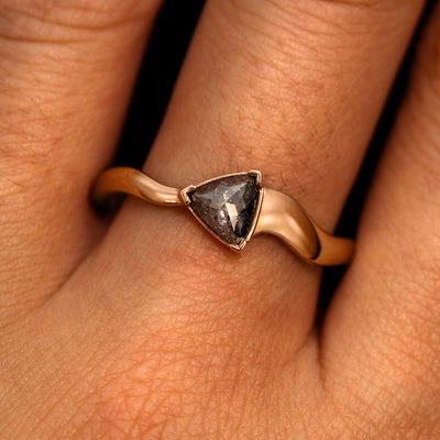 A model's hand wearing a 14k rose gold Trillion Salt and Pepper Diamond Wavy Ring