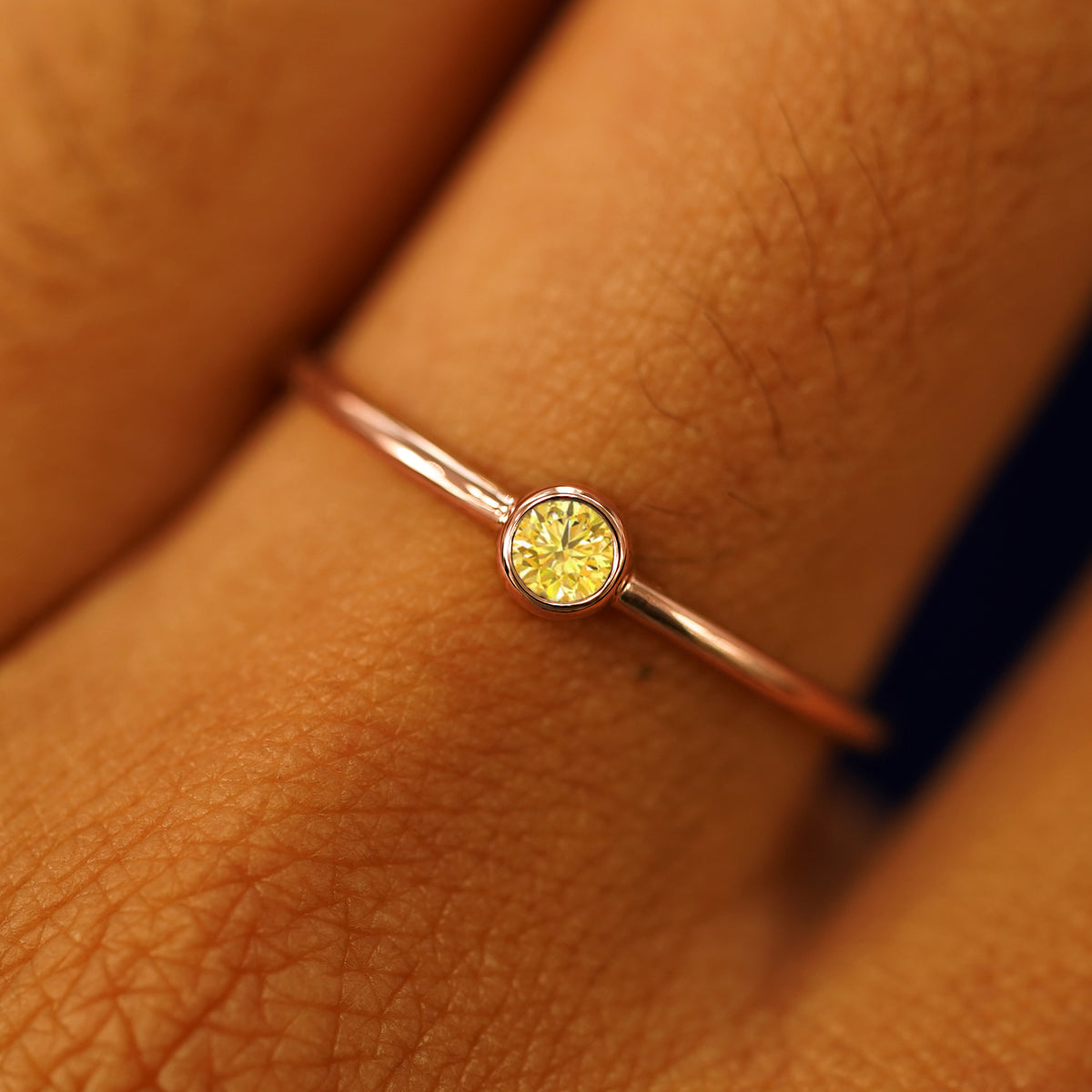 Close up view of a model's fingers wearing a 14k rose gold Yellow Diamond Ring