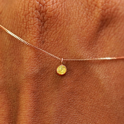 Close up view of a 14k rose gold Yellow Diamond Necklace draped across the back of a model's hand