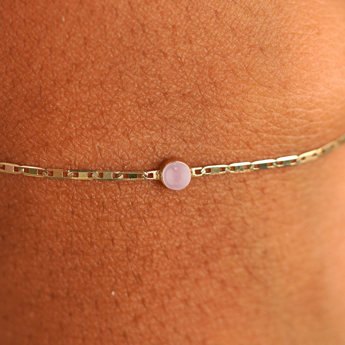 Close up view of a models wrist wearing 14k yellow gold Rose Quartz Bracelet